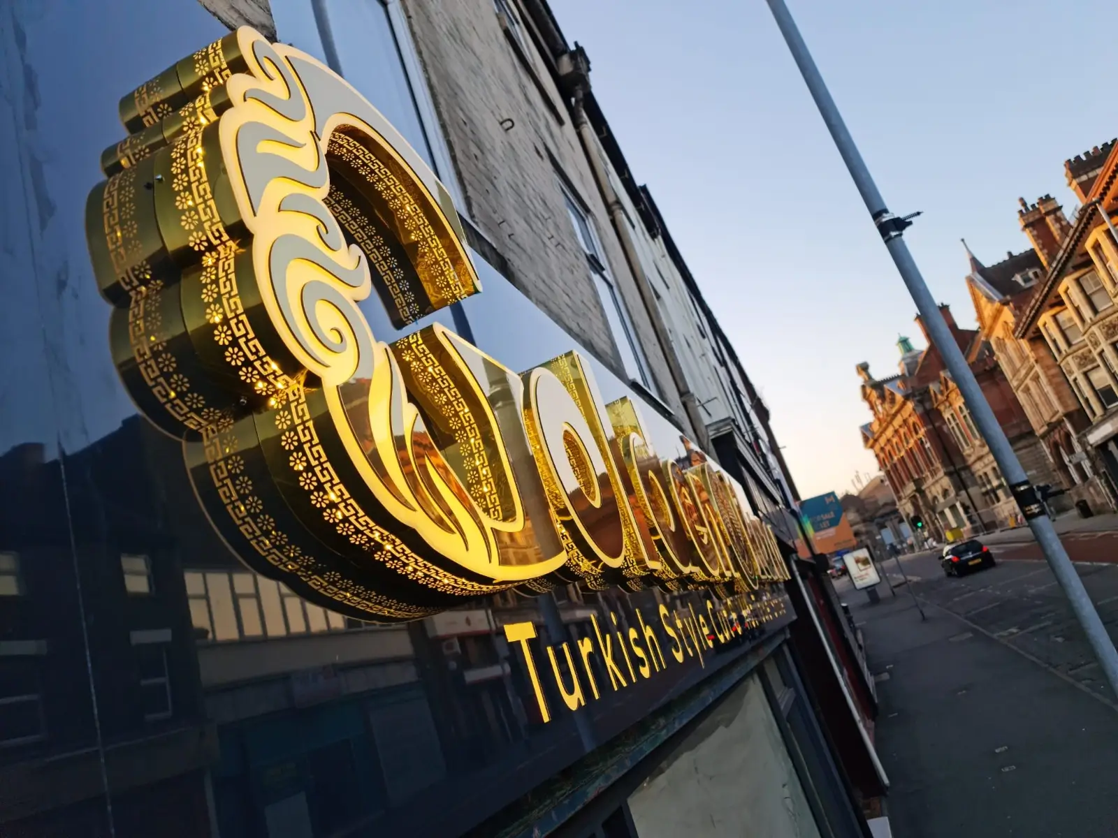 Golden sign affixed to the side of a building, reflecting sunlight and enhancing the structure's visual appeal.