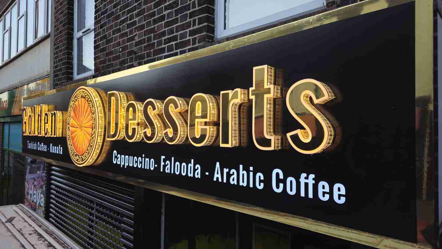 A colorful sign for a dessert shop mounted on a building, featuring images of cakes and pastries.