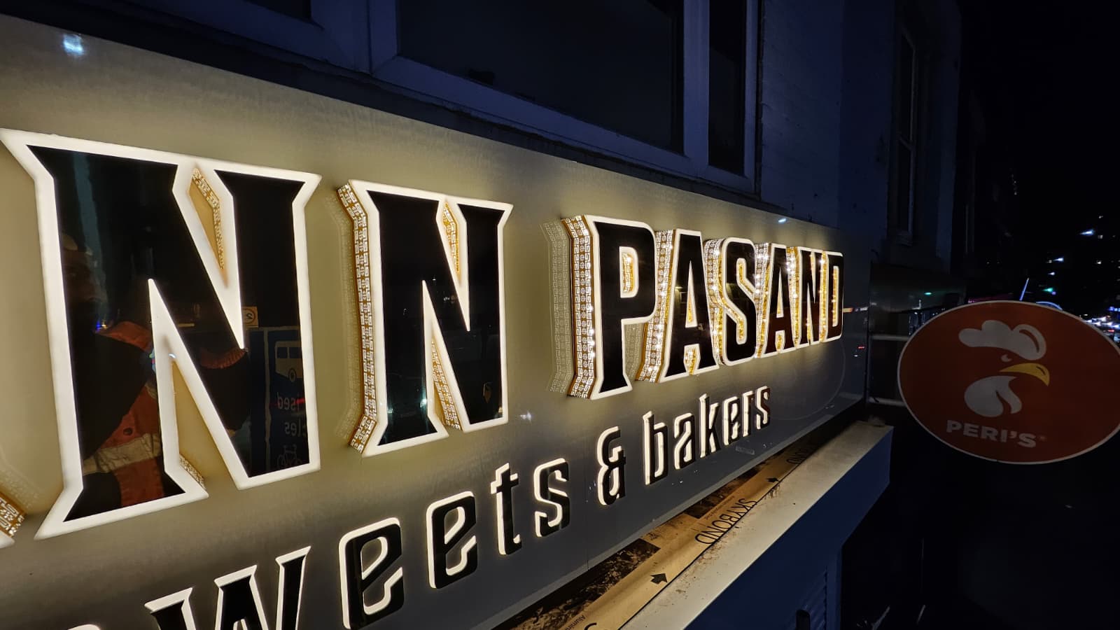 Neon sign reading "Inn Pasan" illuminated in front of a building at night.