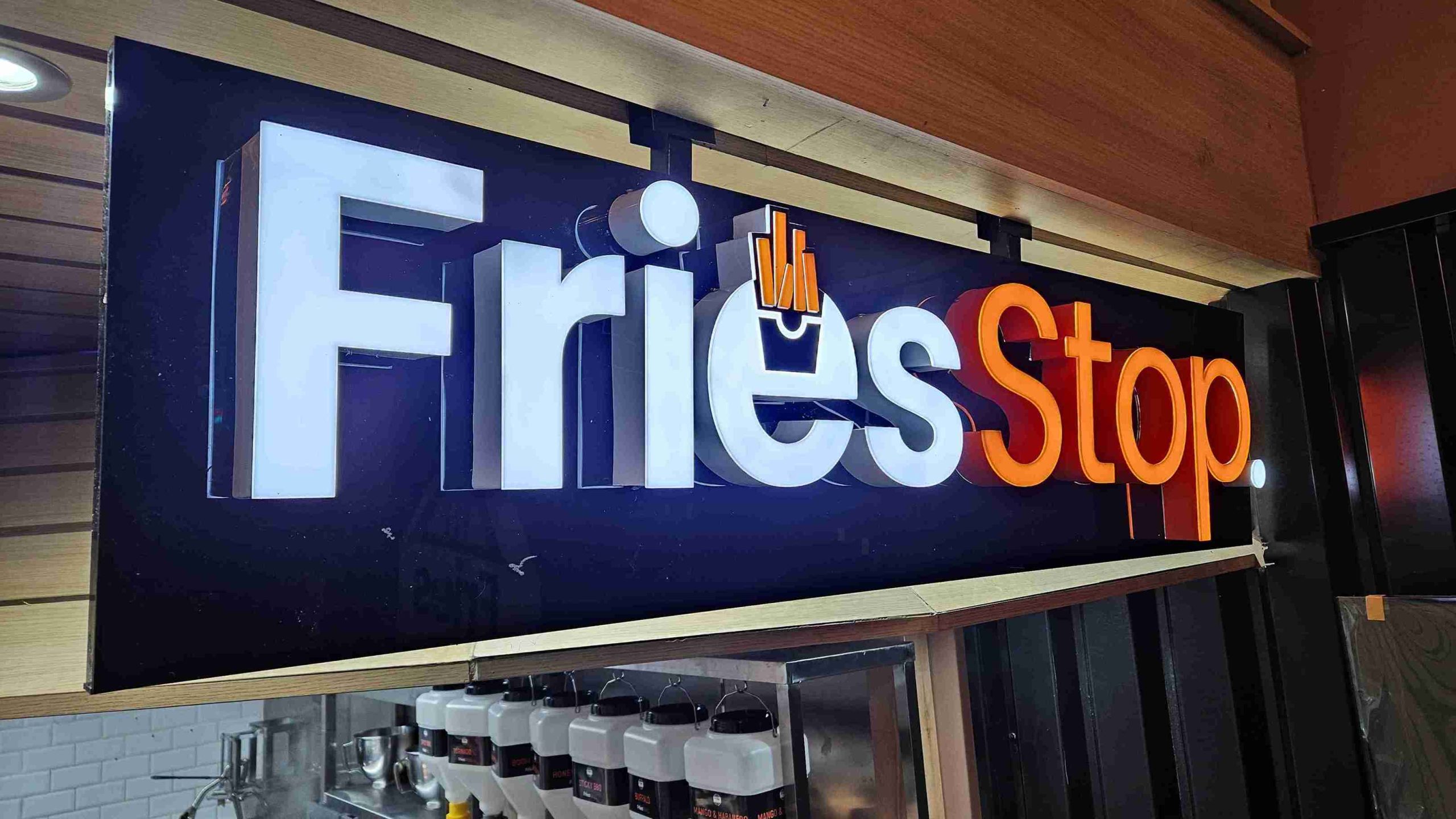 A sign reading "Fries Stop" stands in front of a restaurant, inviting customers to enjoy delicious fries.