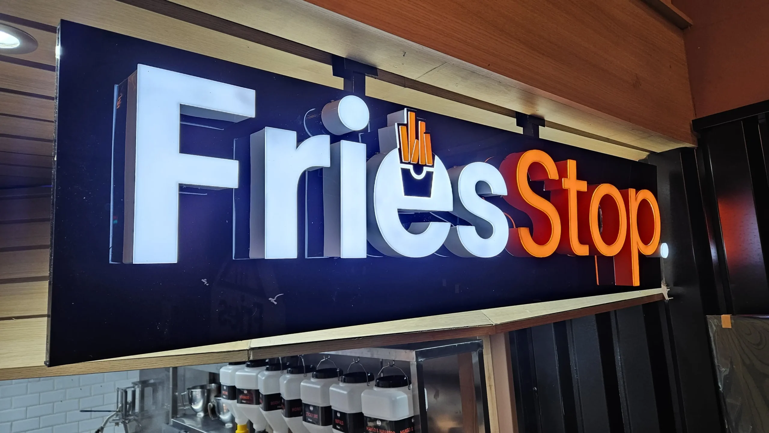 A sign reading "Fries Stop" stands in front of a restaurant, inviting customers to enjoy delicious fries.