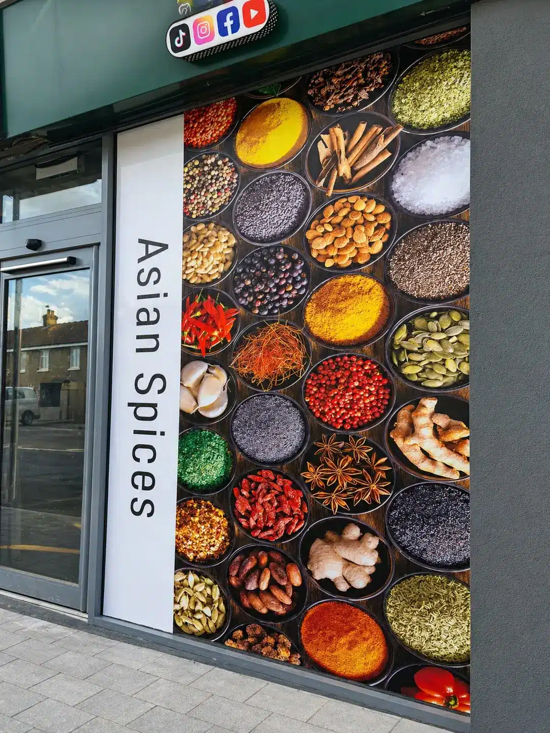 A vibrant window display showcasing an array of colorful spices in jars and containers, inviting passersby to explore.