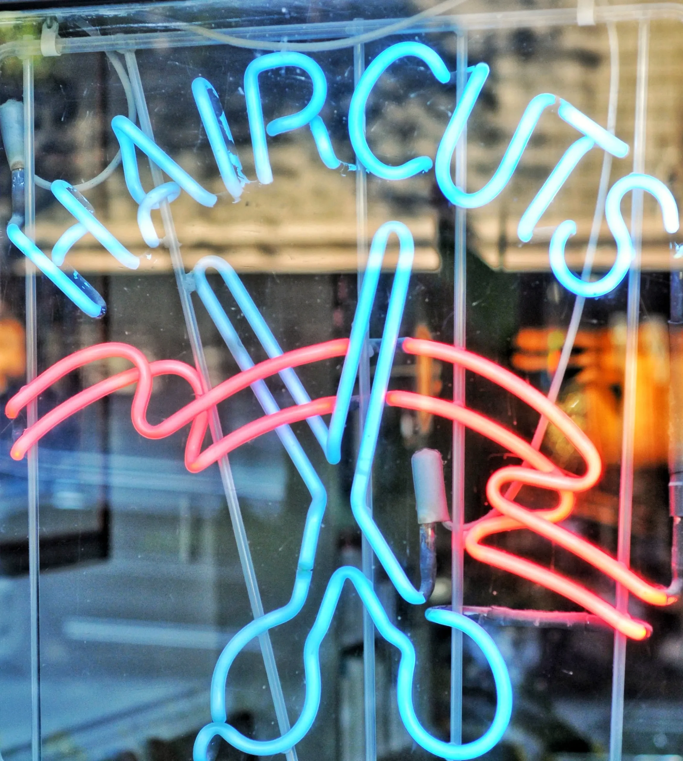 neon haircuts sign glowing in urban window scaled